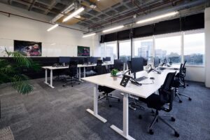 Modern kantoorinterieur aan de Johan Huizingalaan met meerdere werkplekken, grote ramen en uitzicht op kantoorgebouwen.